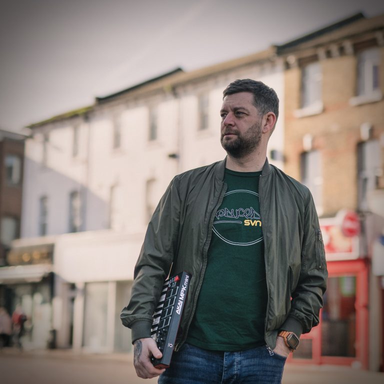 Stu SVNTY6 walking down a street holding a Synth.